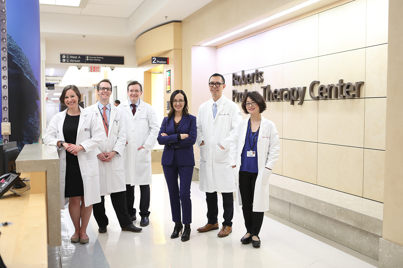 A group of clinicians stands in front of the Roberts Proton Therapy Center clinic