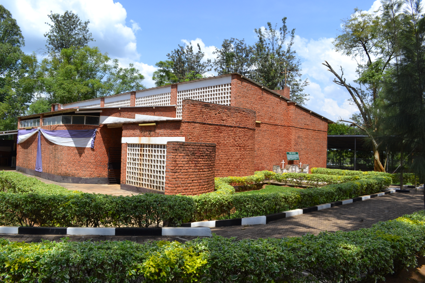 A brick church with shrubbery and a brick path.