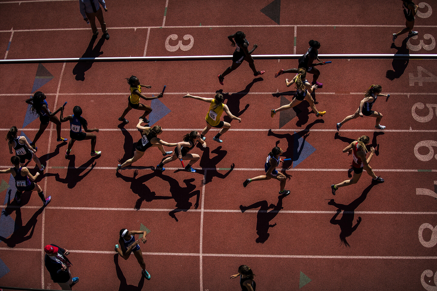 Relay runners pass batons during the 2018 Penn Relays.