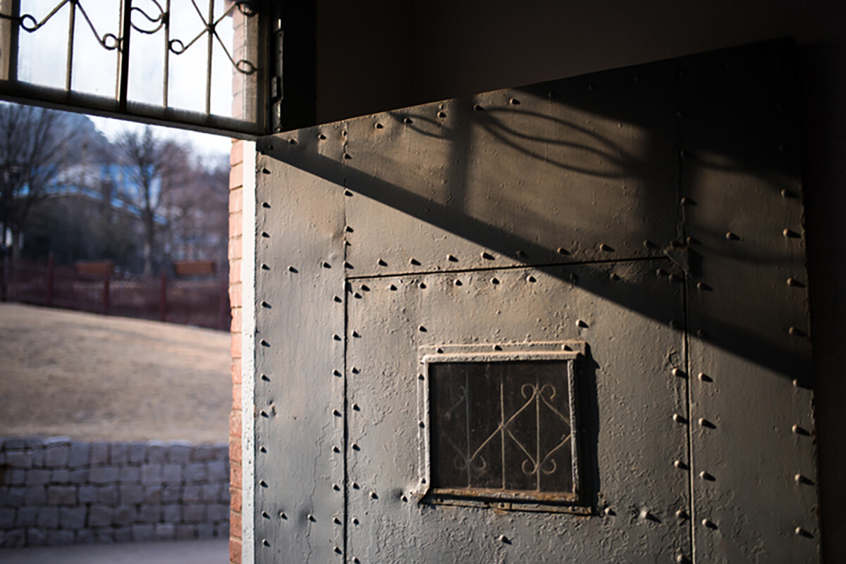 Open prison door with sunlight coming in and outside city in background