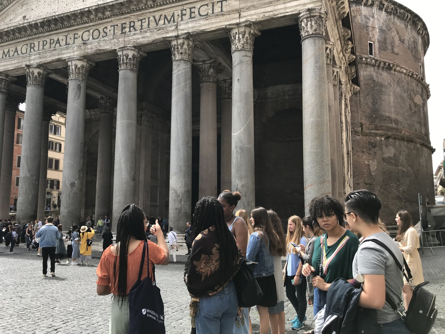 A group of people standing in front of an iconic building in Rome, Italy.