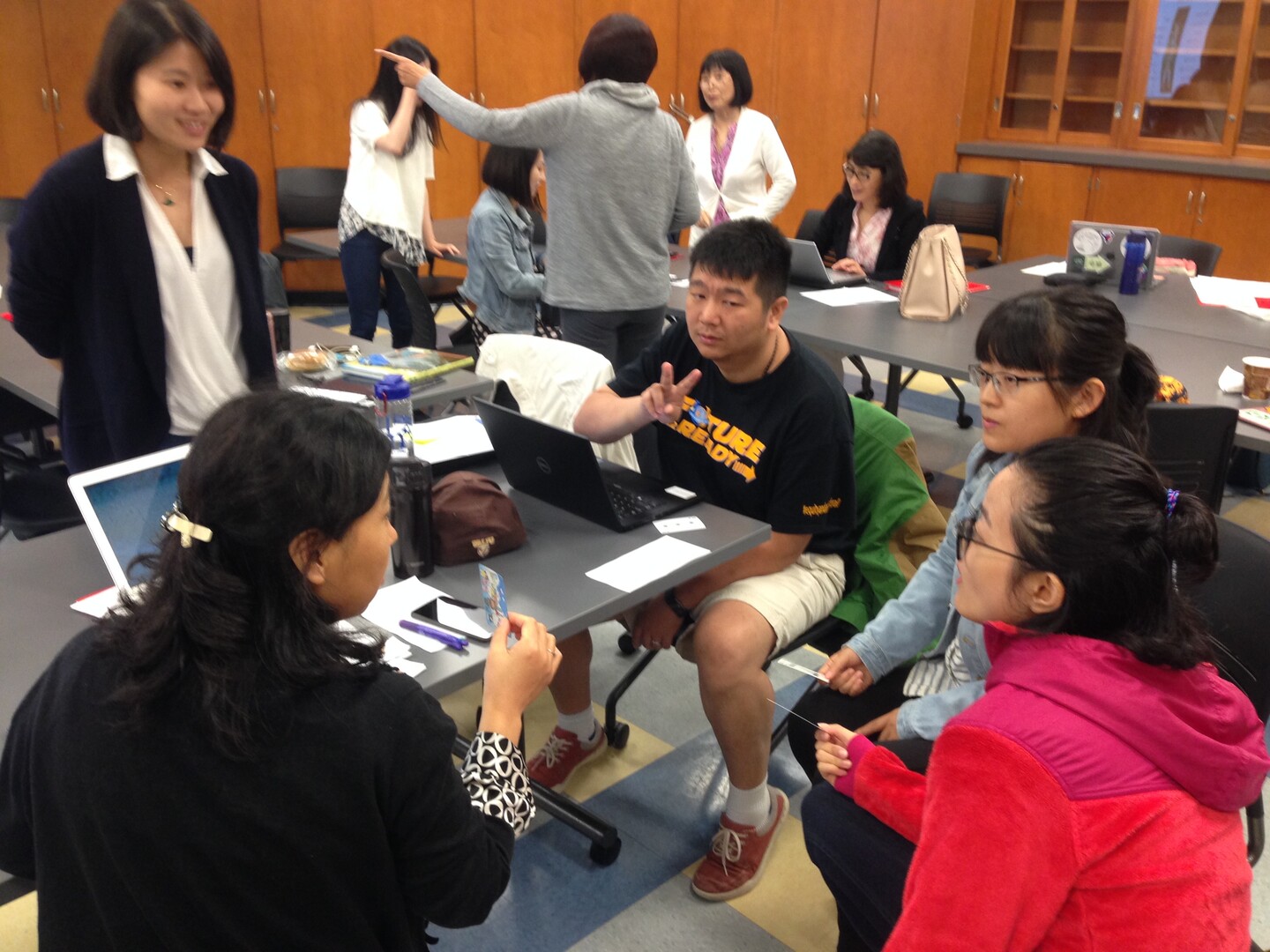 Teachers engage in conversation around a laptop
