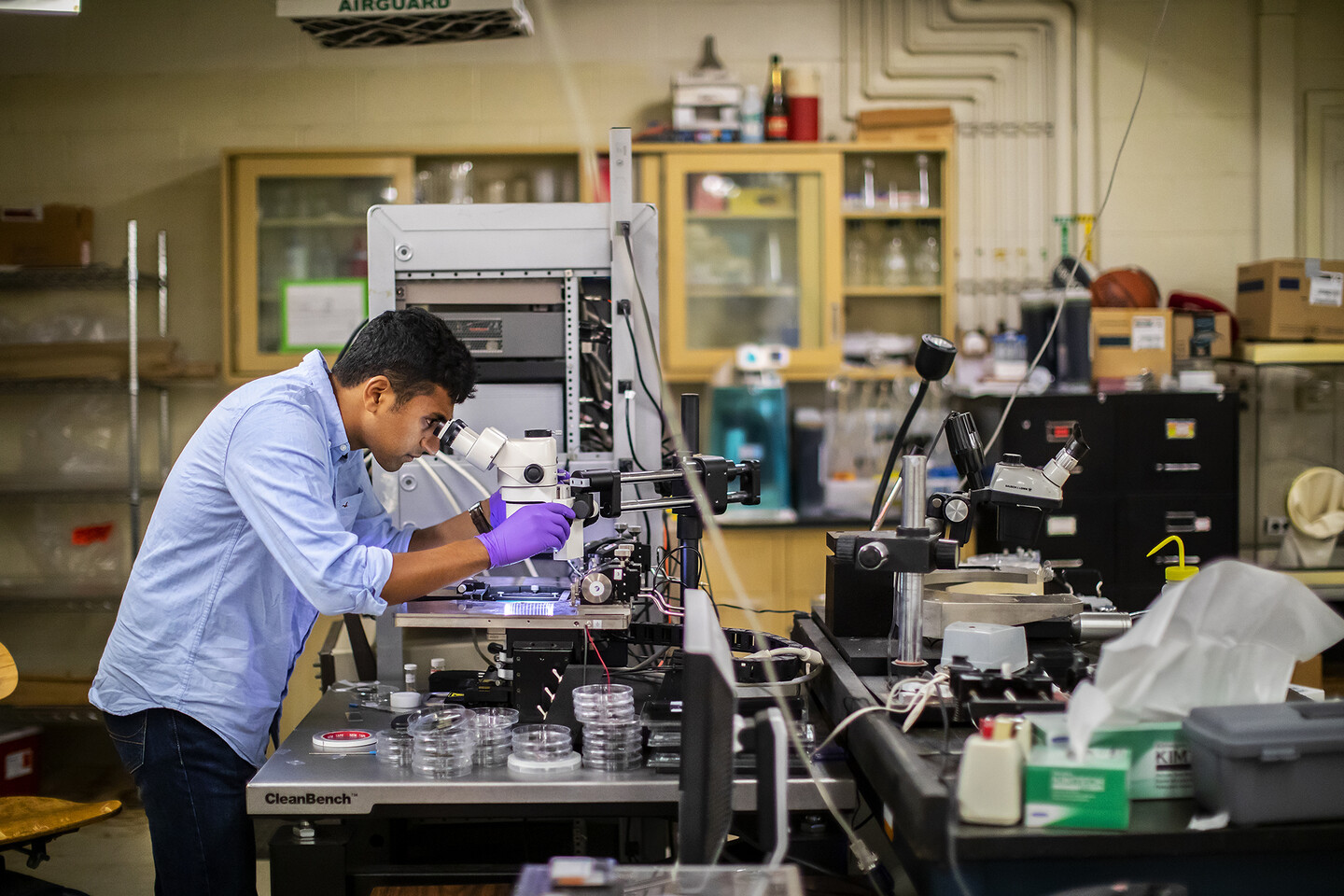a person looking into a microscrope inside of a lab