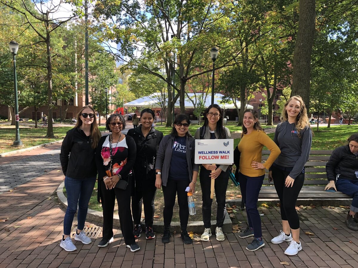 Students gathered on College Green with sign that reads Wellness Walk Follow Me