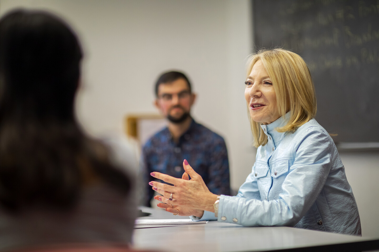 Woman in mid-ground talks to a group while others look on