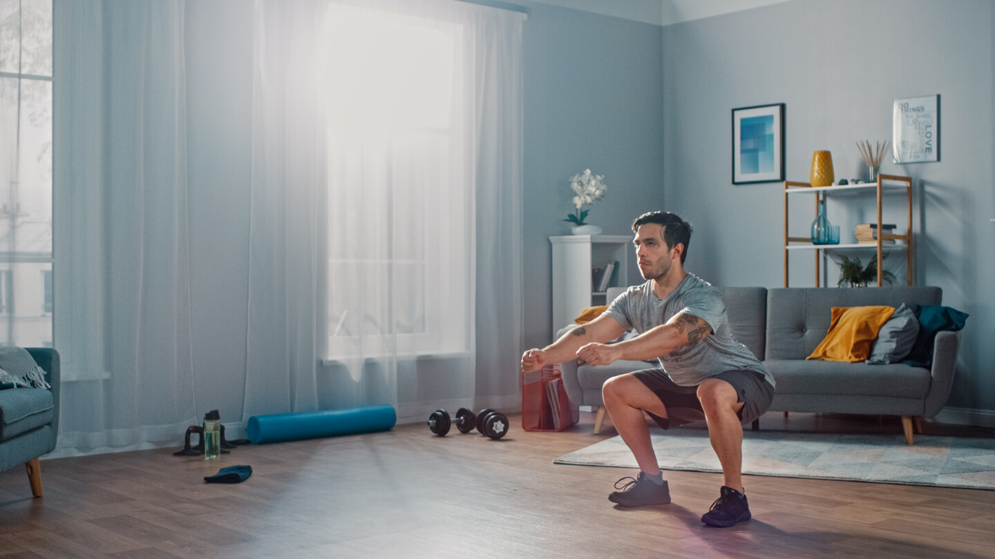 A man does squats in his living room.