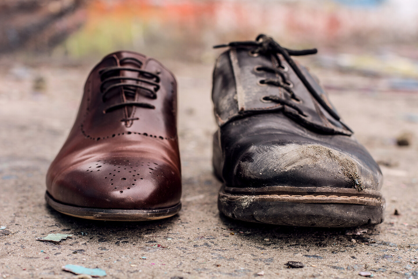 A shiny dress shoe next to a ragged one