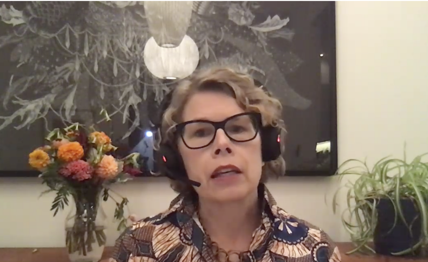 Woman in glasses with a headset addresses a zoom audience