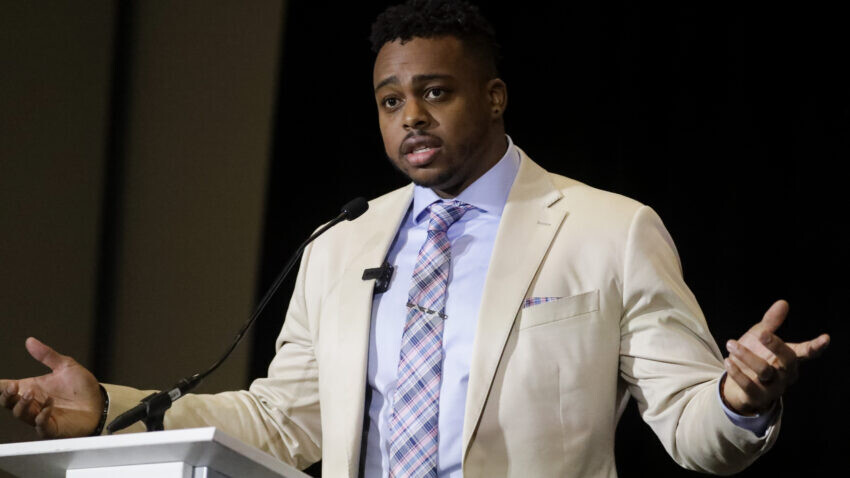 Brandon Copleland speaks while wearing a suit.