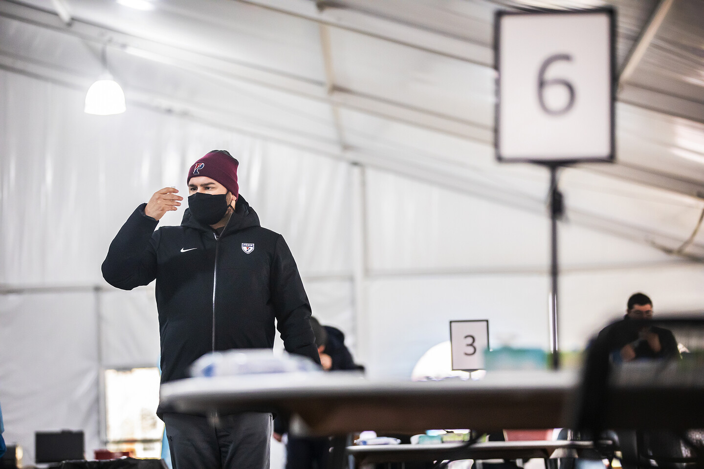 a person wearing a mask studying a tube inside of a massive tent