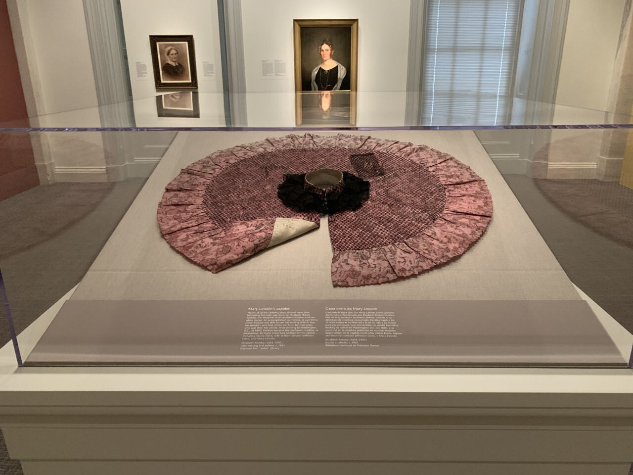 short cape laid flat in a circle in a glass case in a museum exhibition