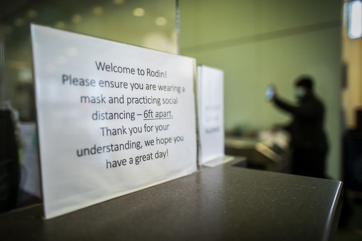 A sign that reads “Please ensure you are wearing a mask and practicing social distancing—6 ft. apart. Thank you for your understanding, we hope you have a great day!”