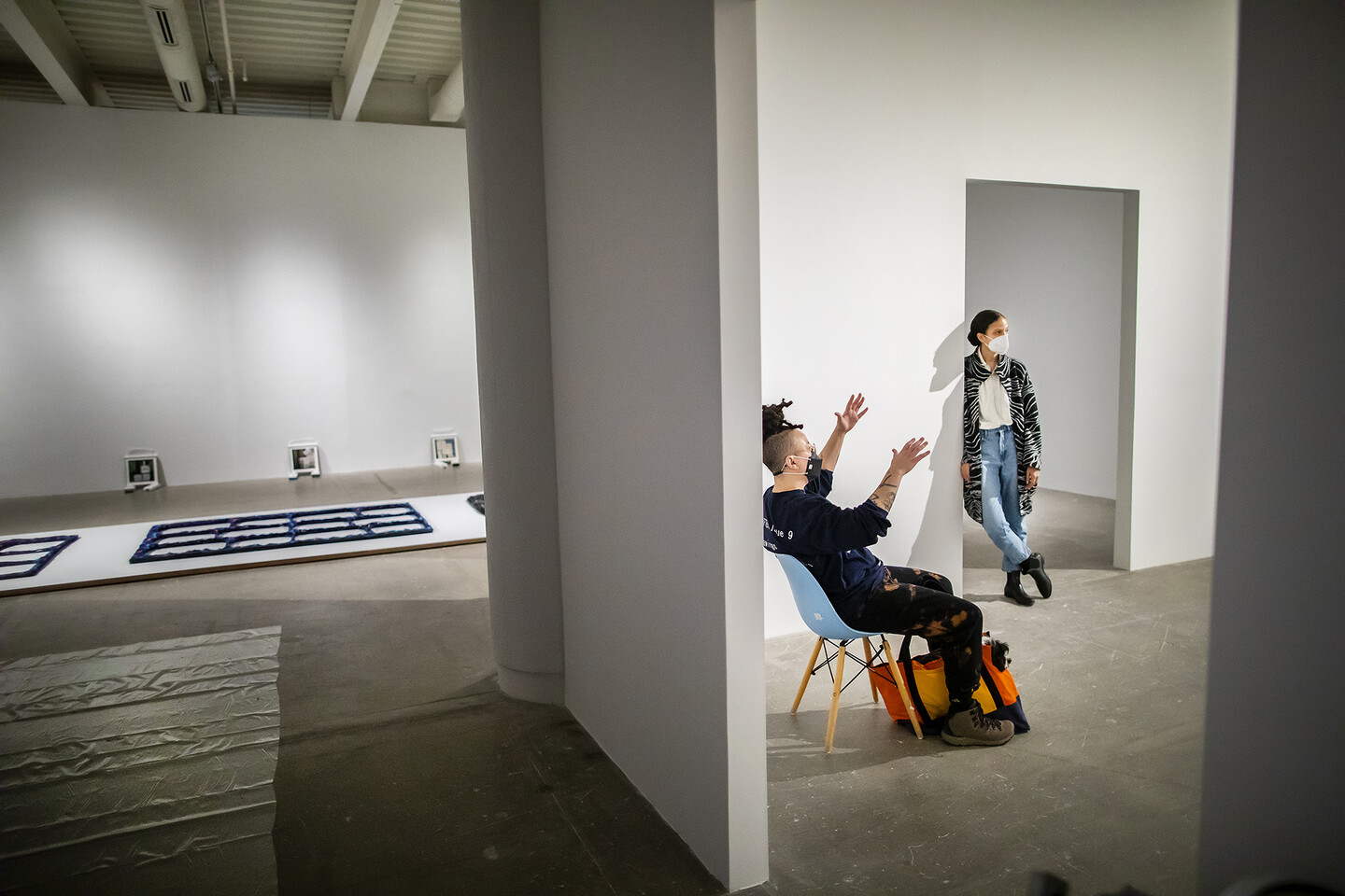 two people talking in museum gallery, one seated and one standing in a doorway