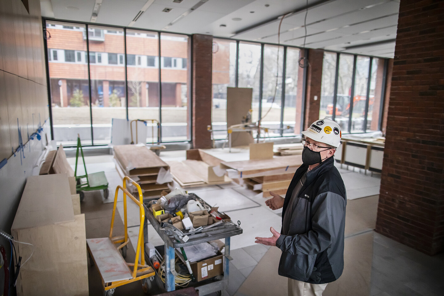 Person in hard hat standing in room with construction materials piled around