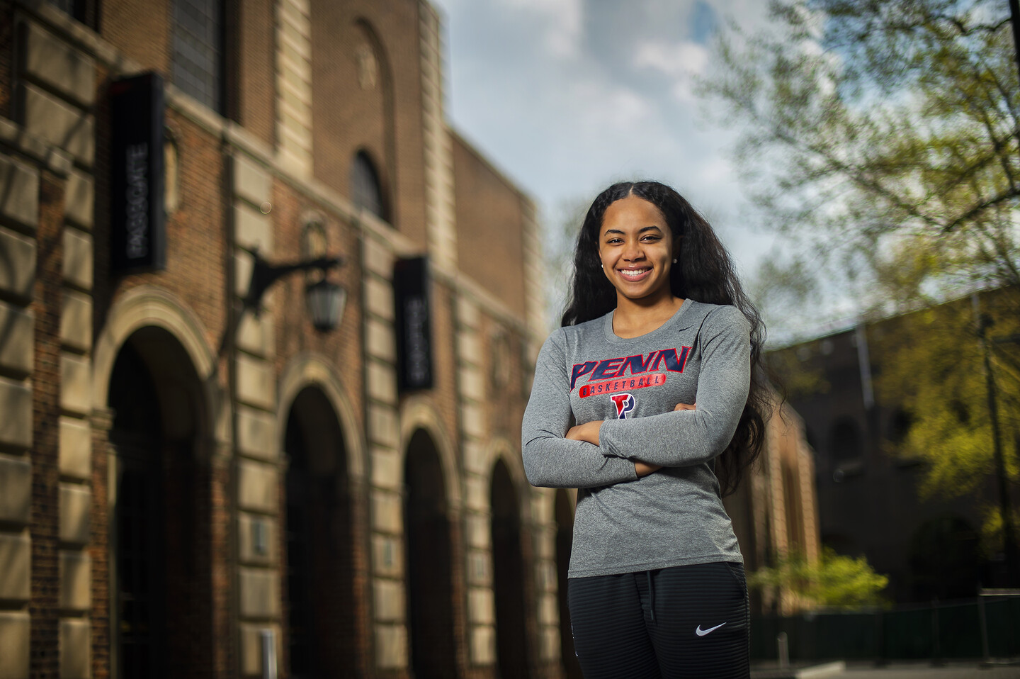 Smiling woman stands with her hands folded on Penn's campus