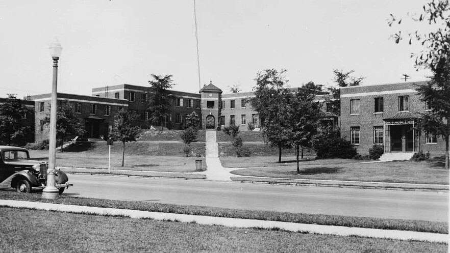 Black and white image of a two-story building with grass and trees in front