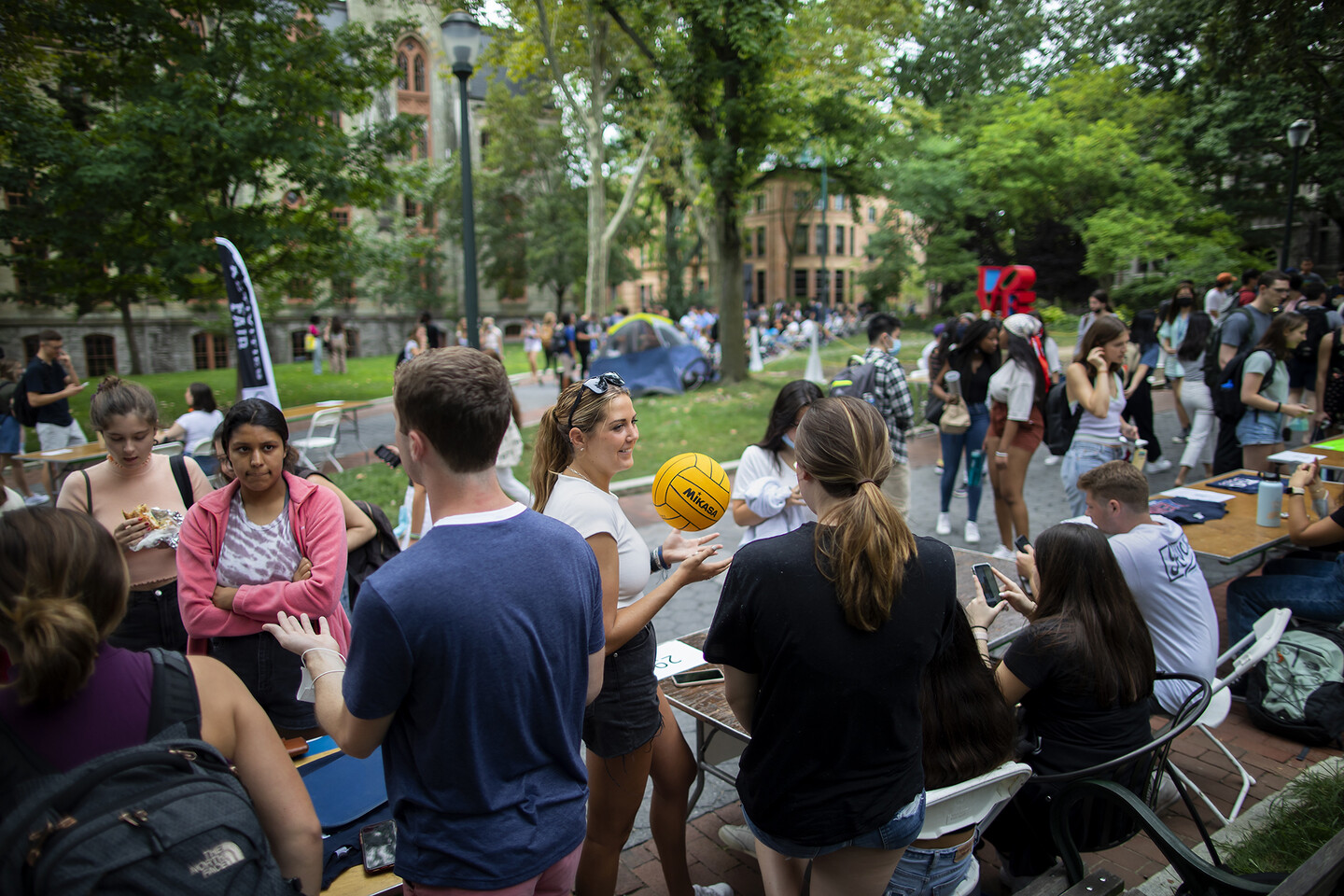 many students along walk outside with tables set up