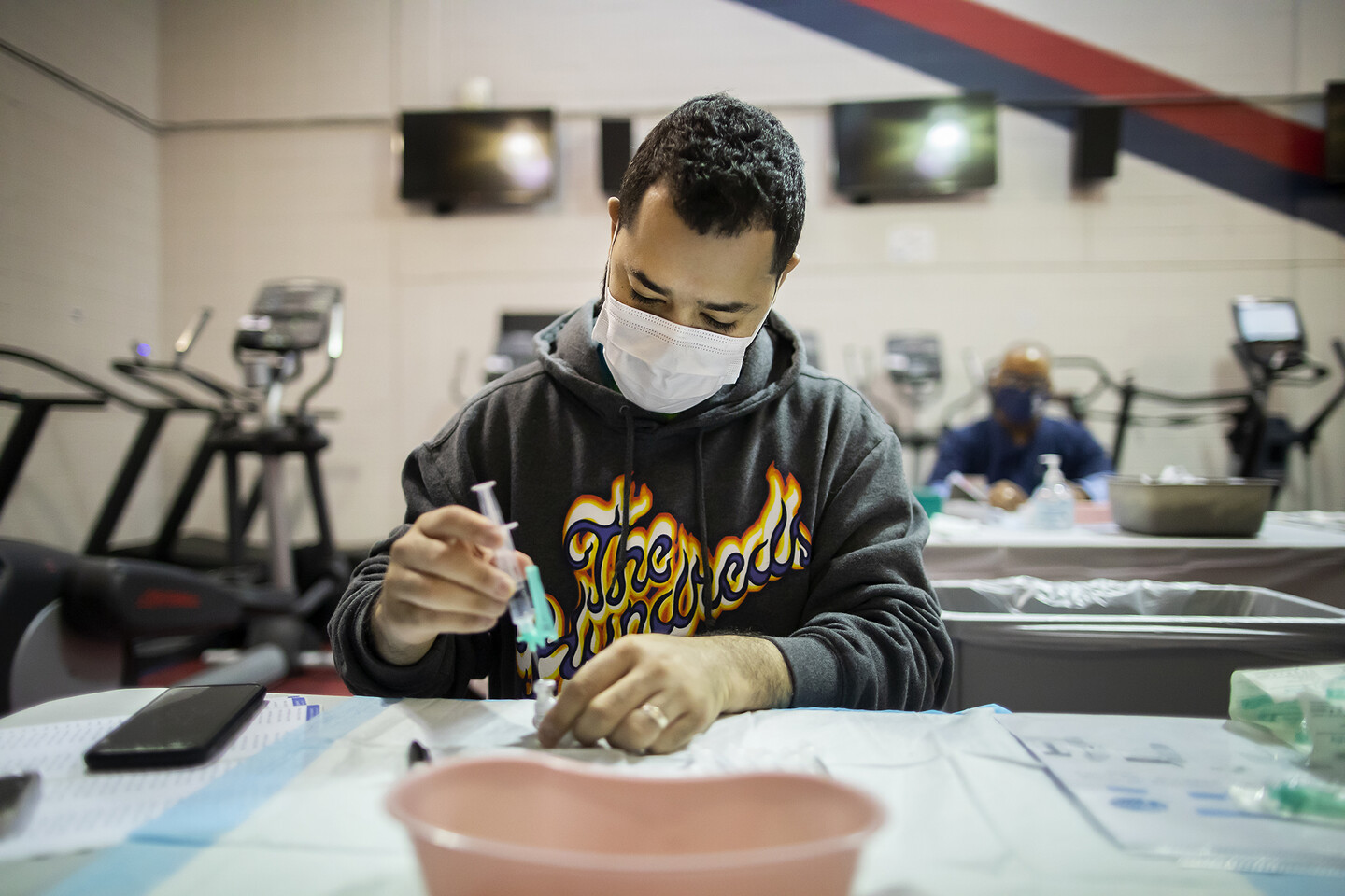 a person in a mask filling a syringe