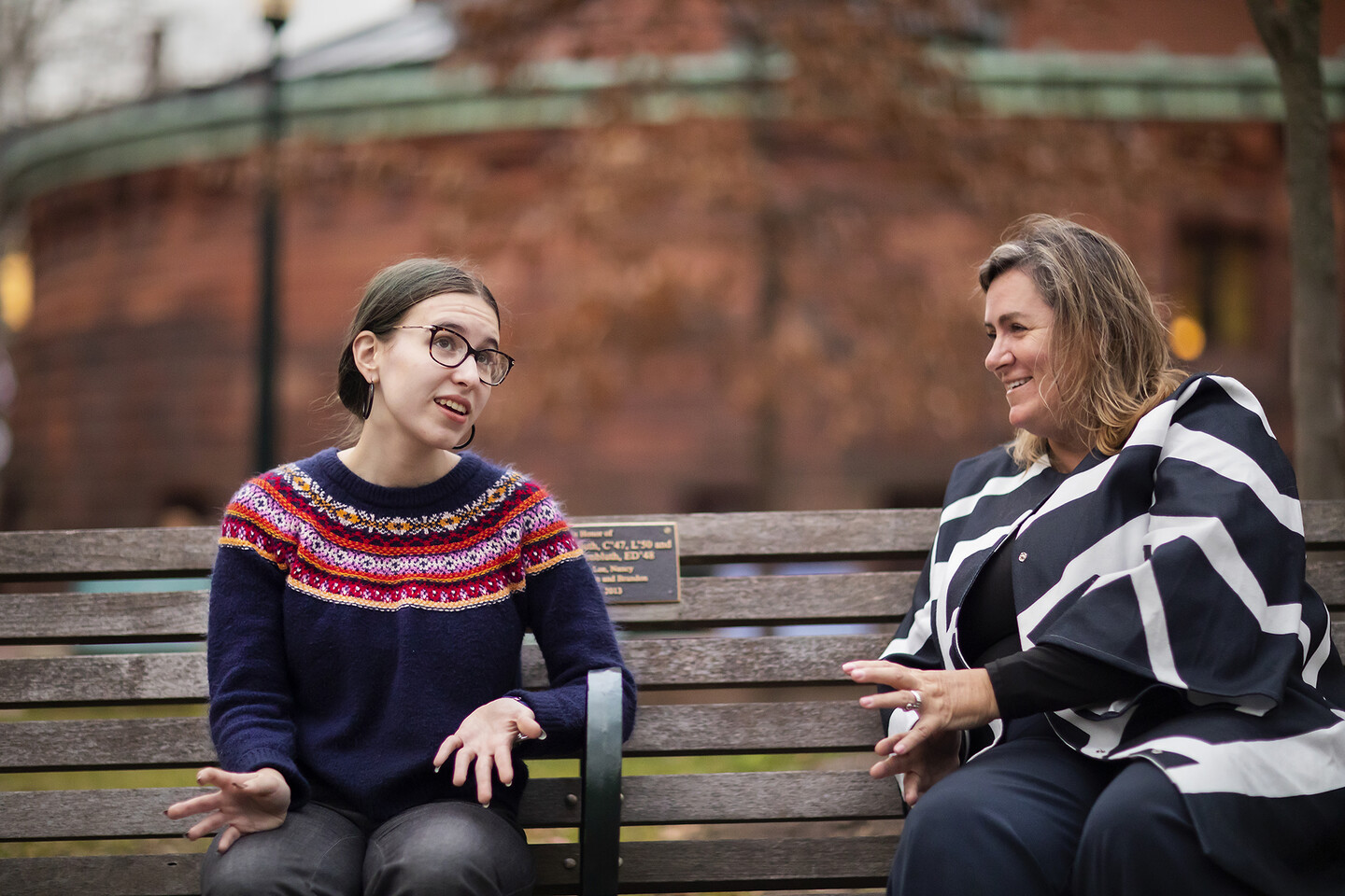 two people sitting on a bench and talking