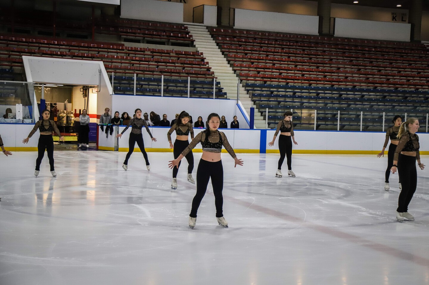 A team of ice skaters wearing sparkly costumes in formation