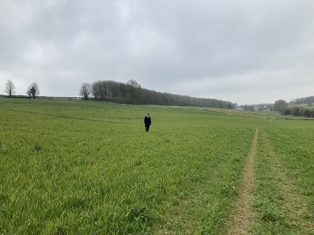 Person standing in a large green field.