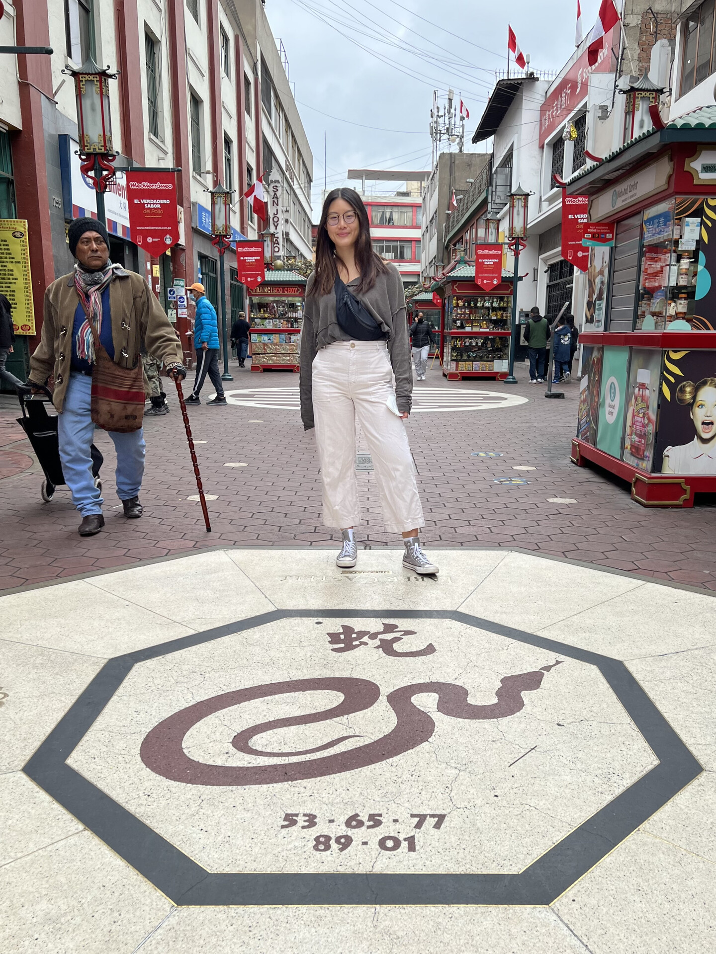 Adrian Ke in Lima's Chinatown, standing on a street with a snake symbol embedded into the cement