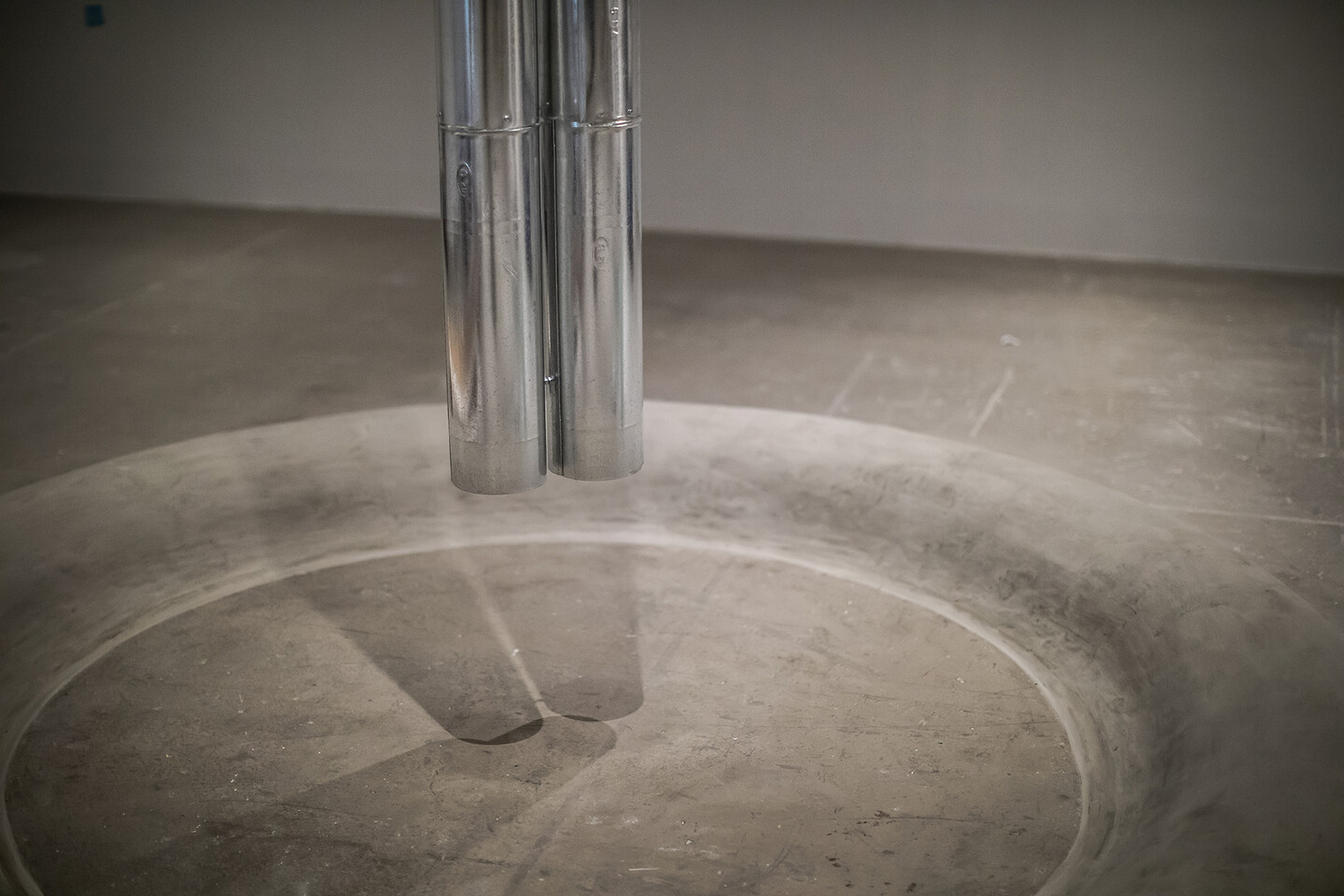A pipe descending from the ceiling over concrete