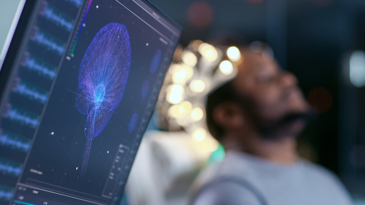 A computer screen displays the brain activity of a man with electrodes on his head.