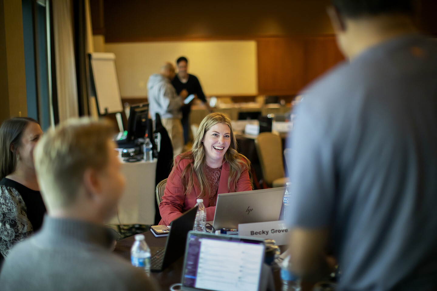 Becky Grove sitting at a table with other people with her laptop open in front of her