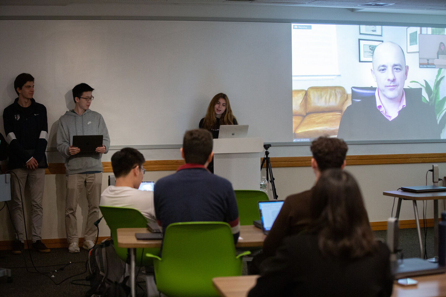 Penn undergrad Sophie Powell stands at a podium with a zoom screen of Evan McMullin behind her as she participates in a mock 2024 Presidential Republican Primary debate. 