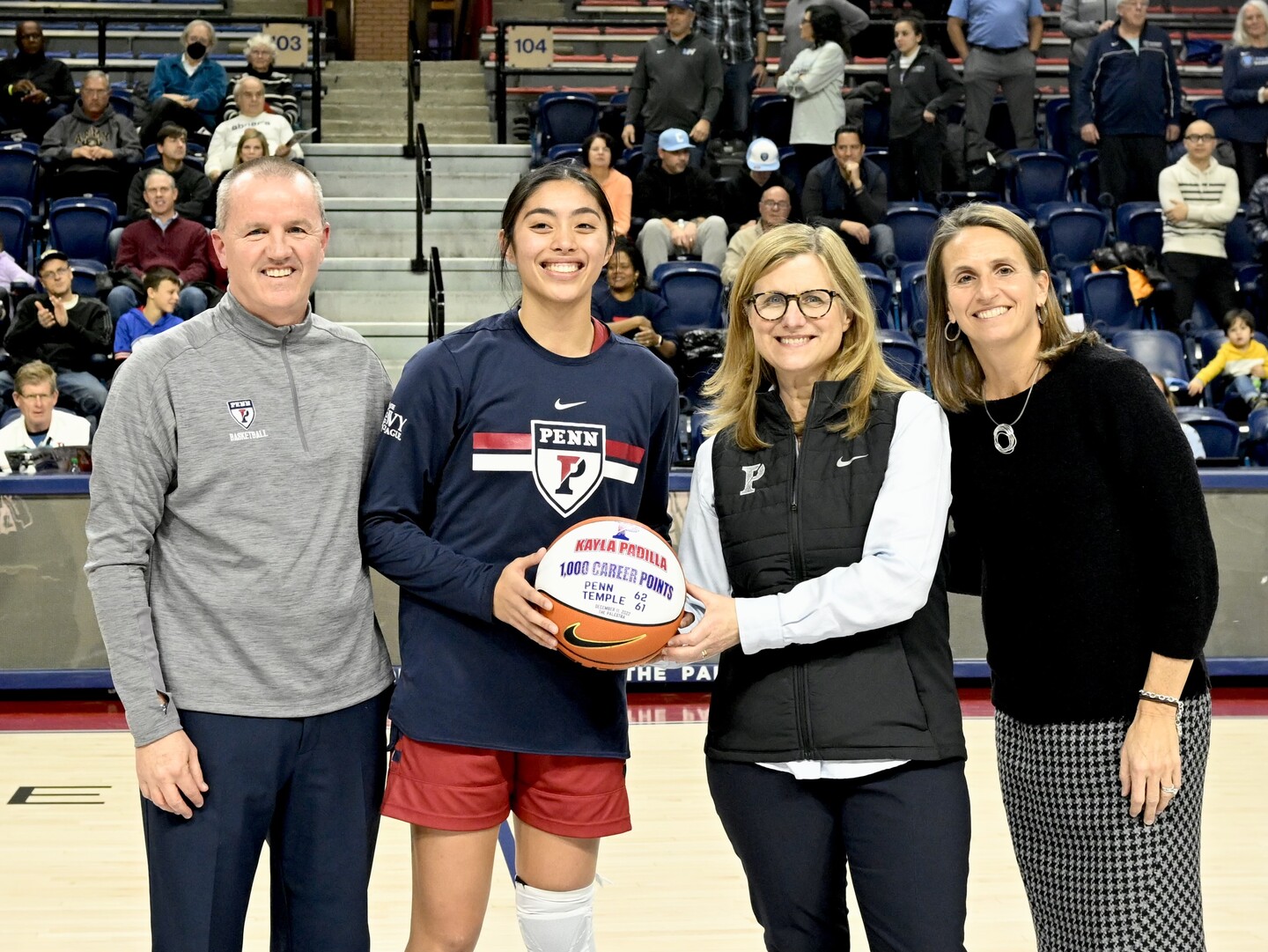 From left, Head Coach Mike McLaughlin, fourth-year guard Kayla Padilla, President Liz Magill, and Athletic Director Alanna Shanahan celebrate Padilla’s 1,000th point during halftime of the Columbia game.