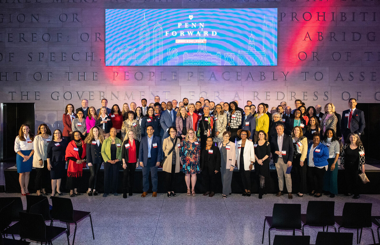 host committee stands on stage with screen in background that reads "Penn Forward Philadelphia"