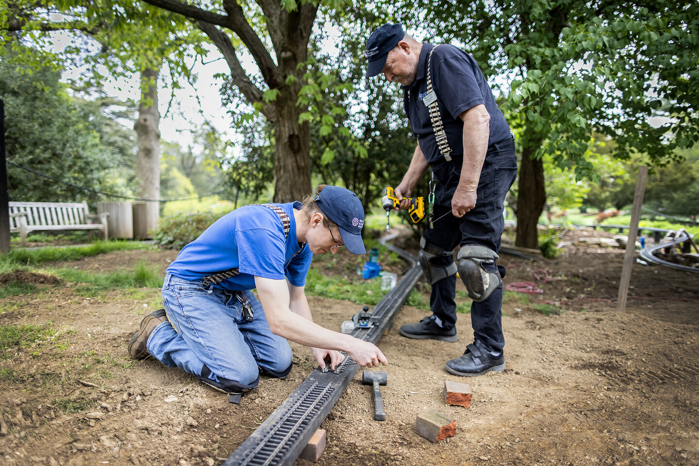 Josh Faia and Bruce Morrell hover over miniature railway track.
