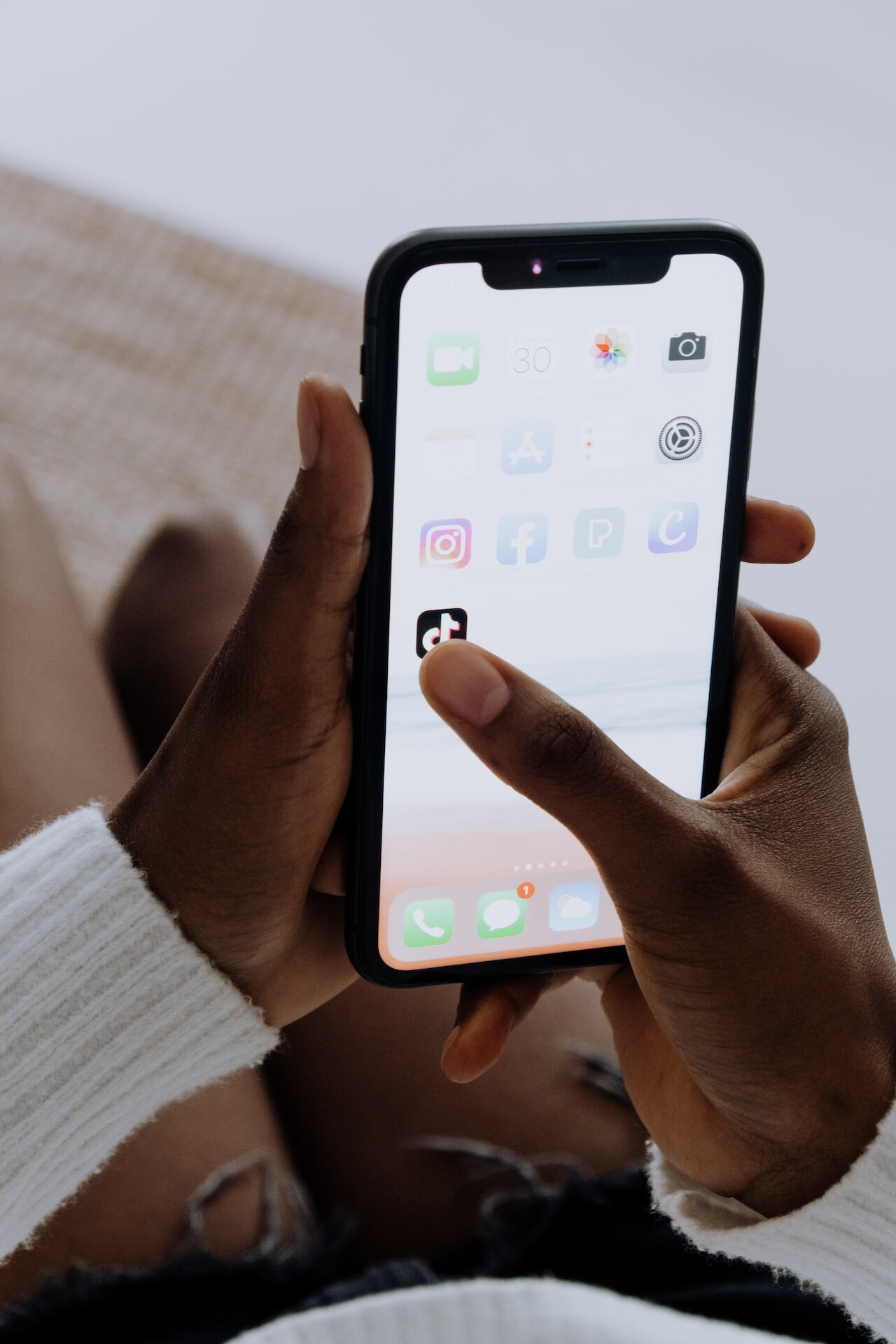 A woman touching the TikTok app on her phone