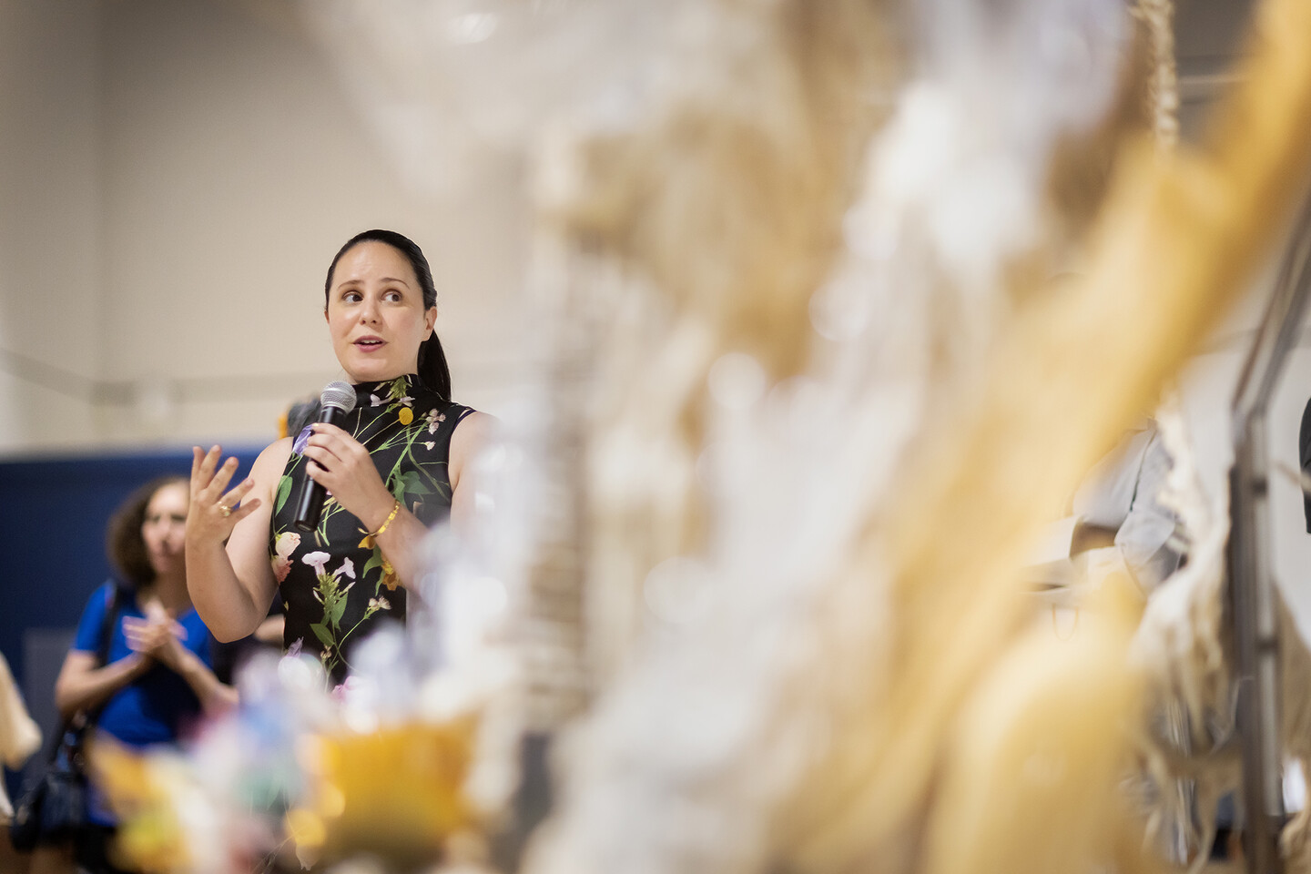 Curator Emily Zimmerman standing in gallery speaking into microphone