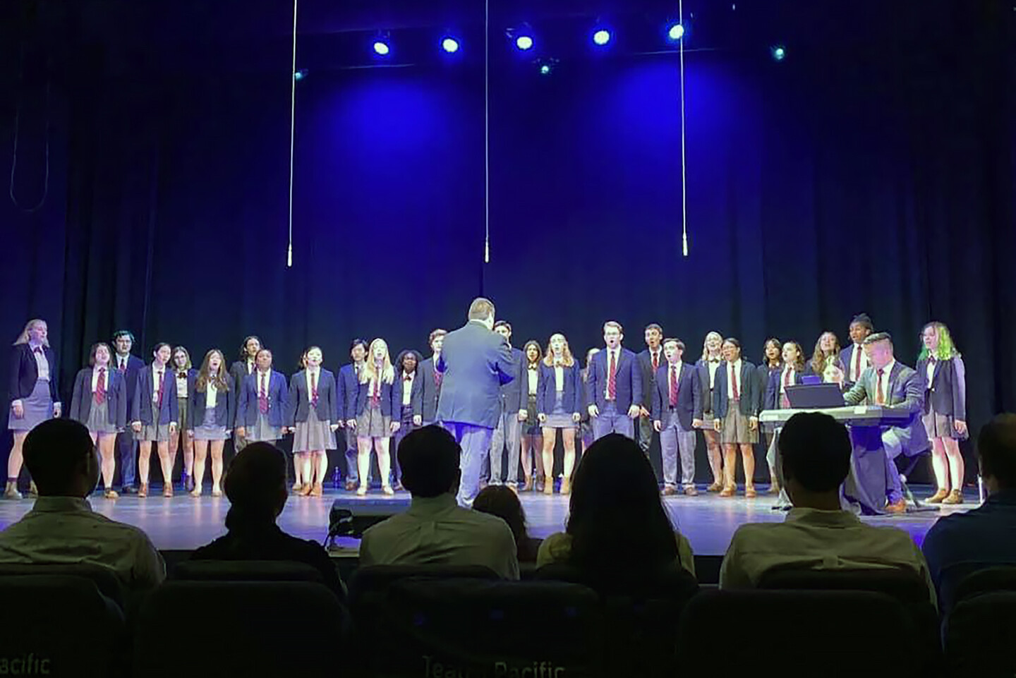 choir singing on stage with audience members in front of them