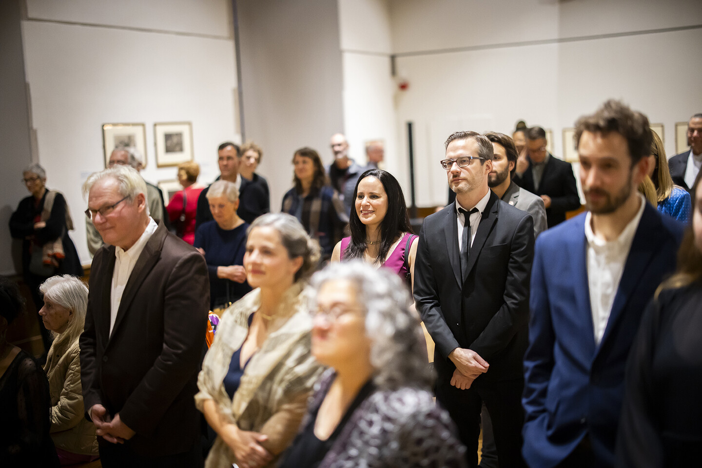 A crowd standing in the art gallery. 