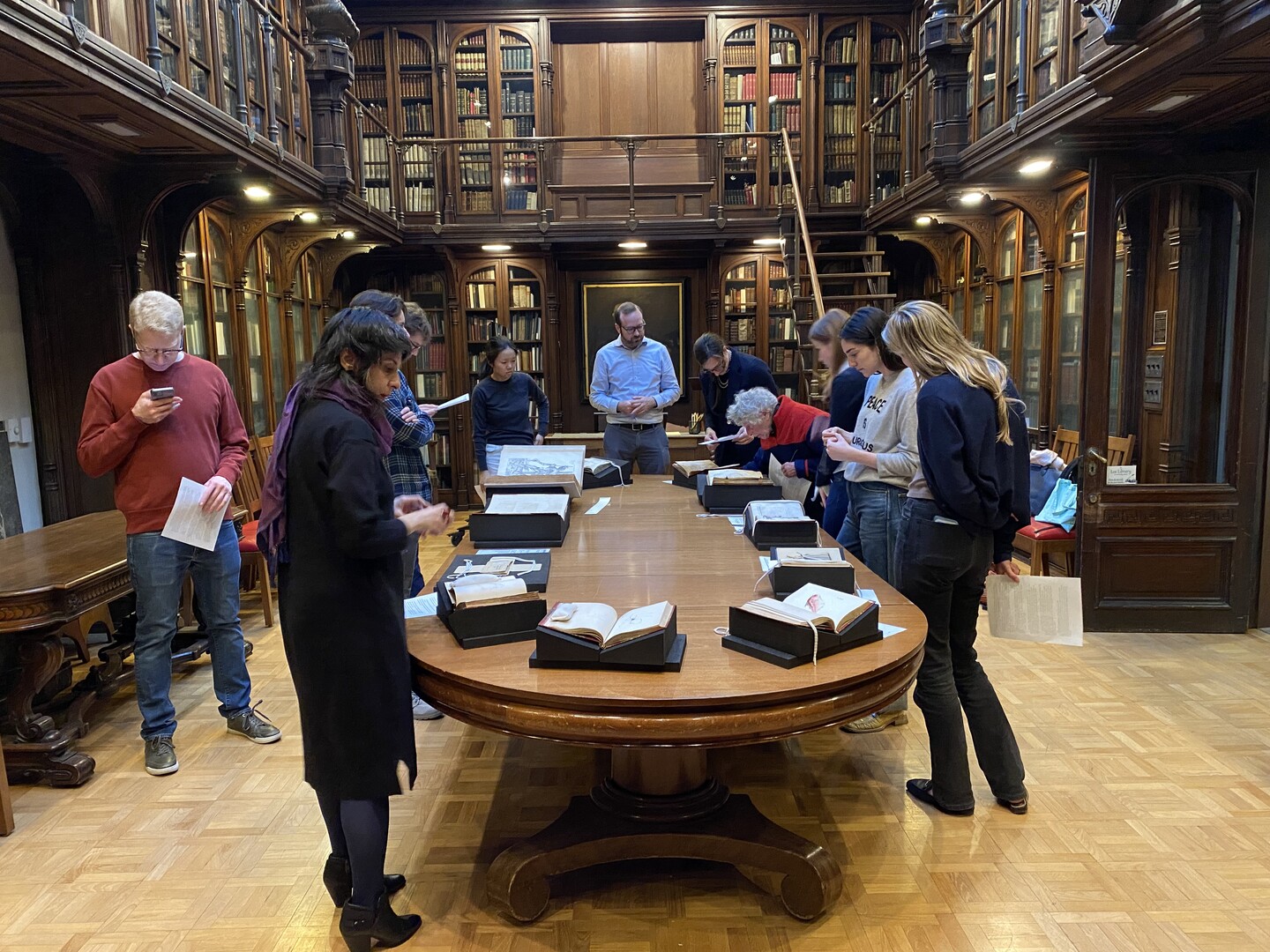 People lookiing at books on a table in a historic library. 