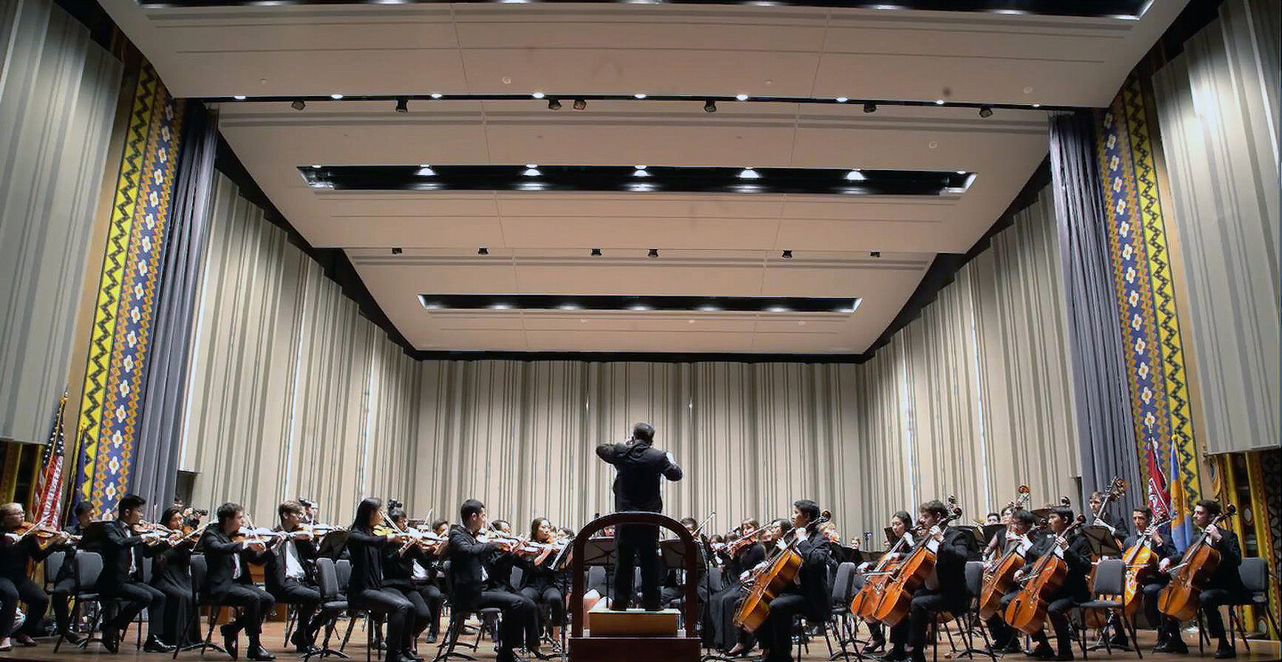 musicians on a stage with a conductor on the podium