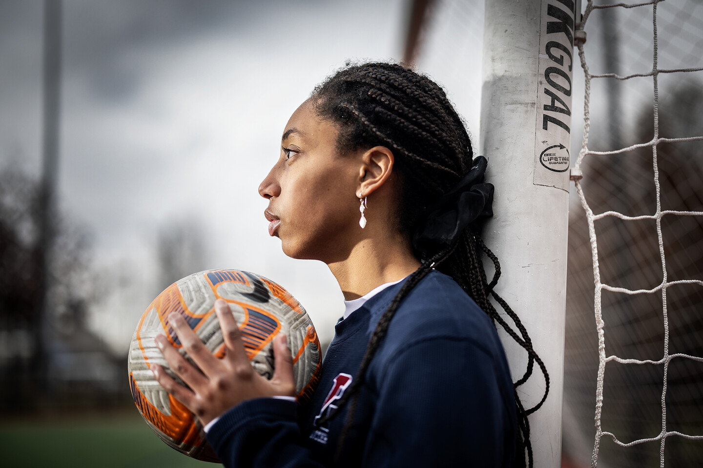 Ginger Fontenot holds a soccer ball in her hands while leaning up against a goalpost at Penn Park.
