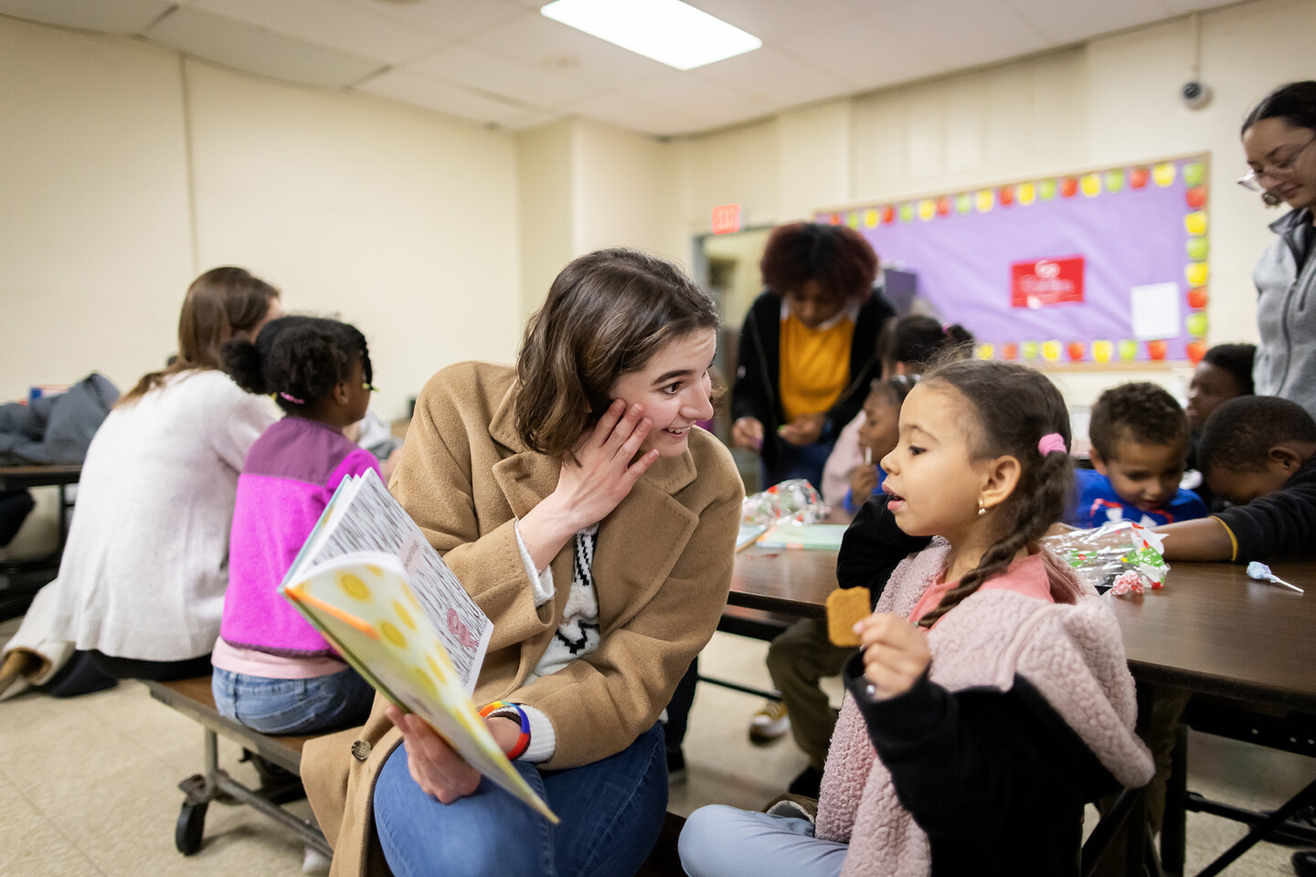 Katherine Taylor reads to a student sitting at cafeteria tables