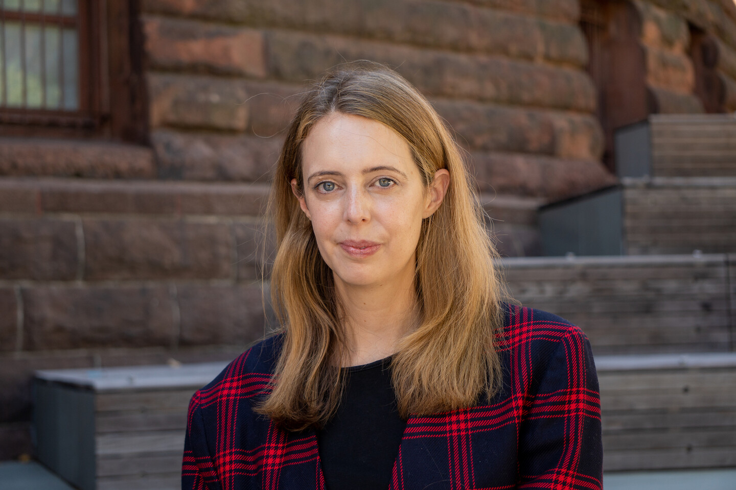 Rachel Hulvey stands in front of a brown stone building and steps.