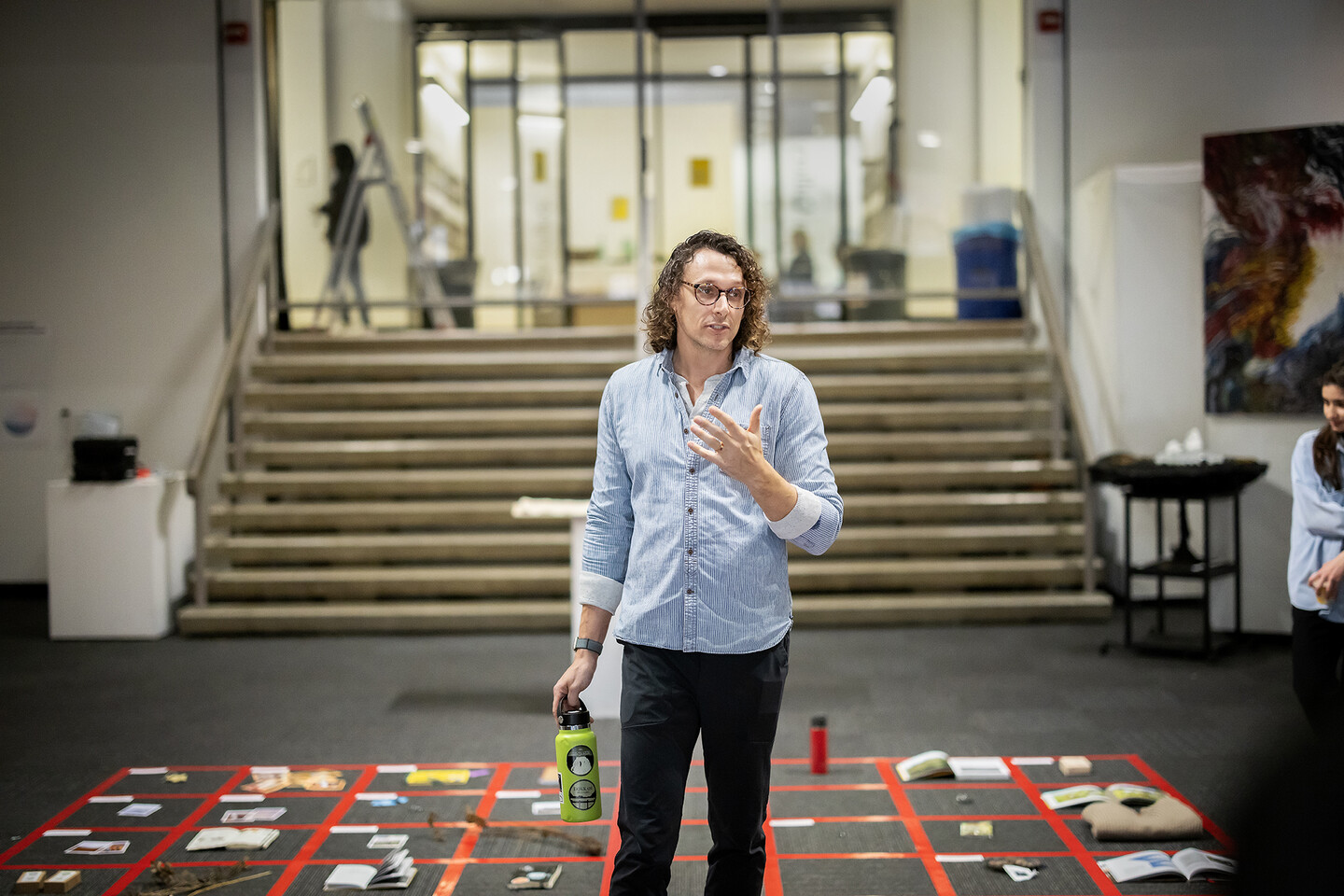 Fleming stands in the middle of a red grid with objects while speaking
