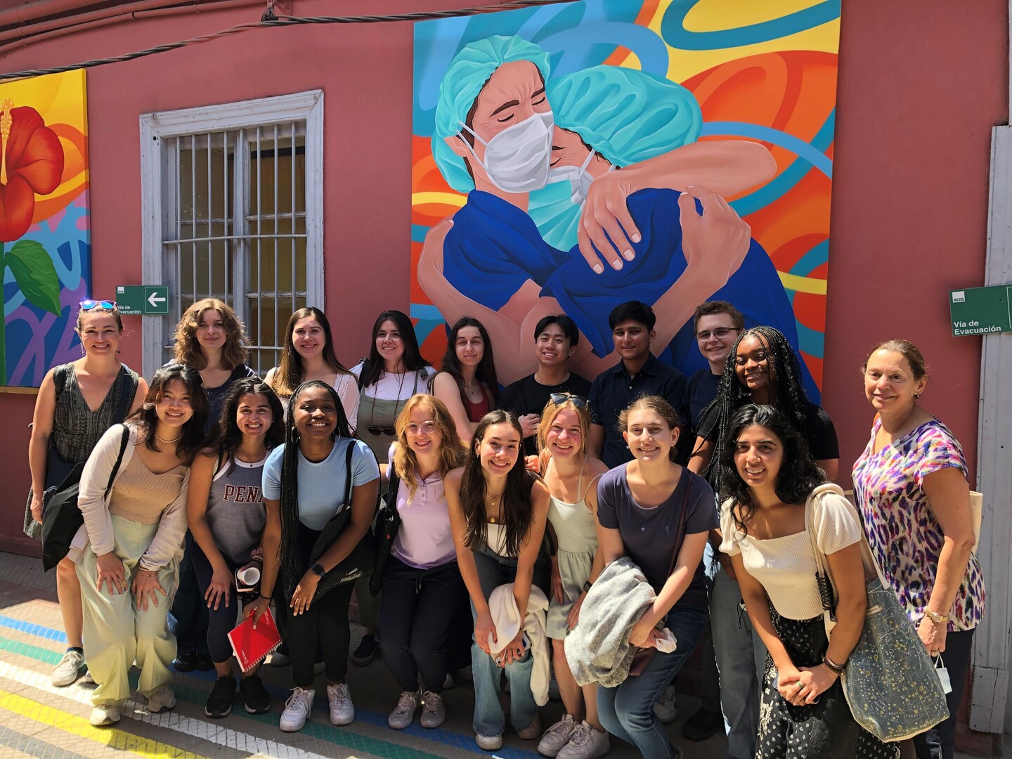 Group photo of Penn students in front of a mural depicting hospital workers embracing.