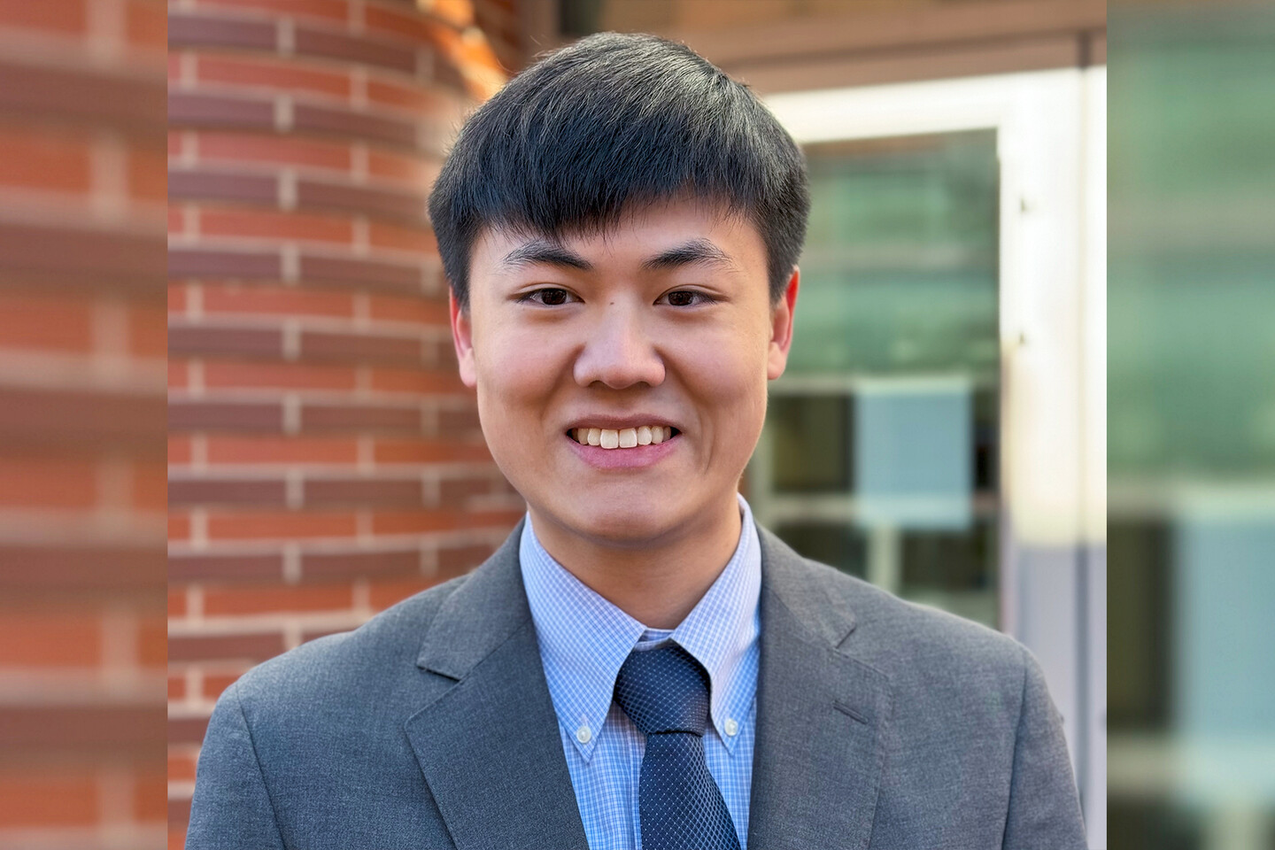 William Niu standing outside in front of a brick wall
