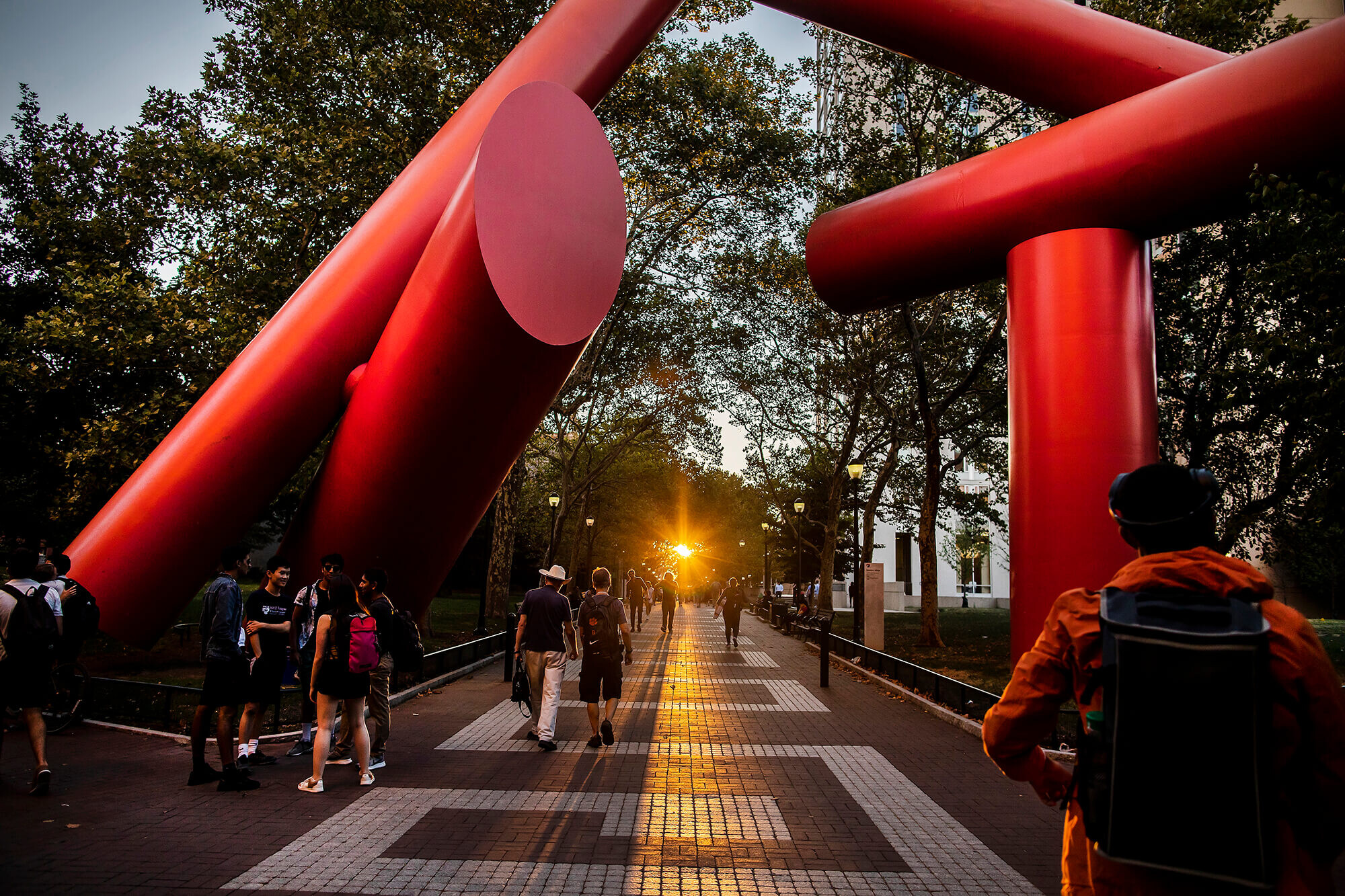 Students walk beneath The Covenant on Locust Walk at dusk