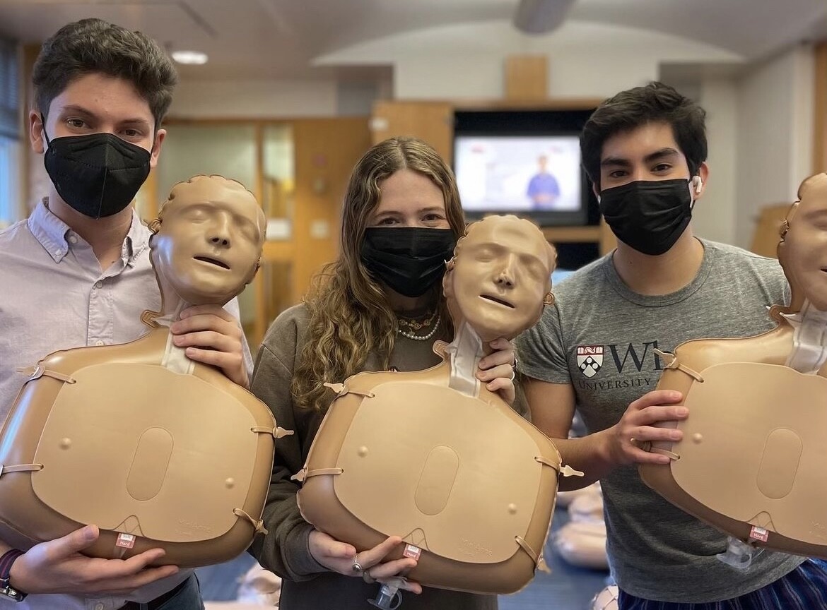 Sarah Katz and two other students hold up CPR manikins.