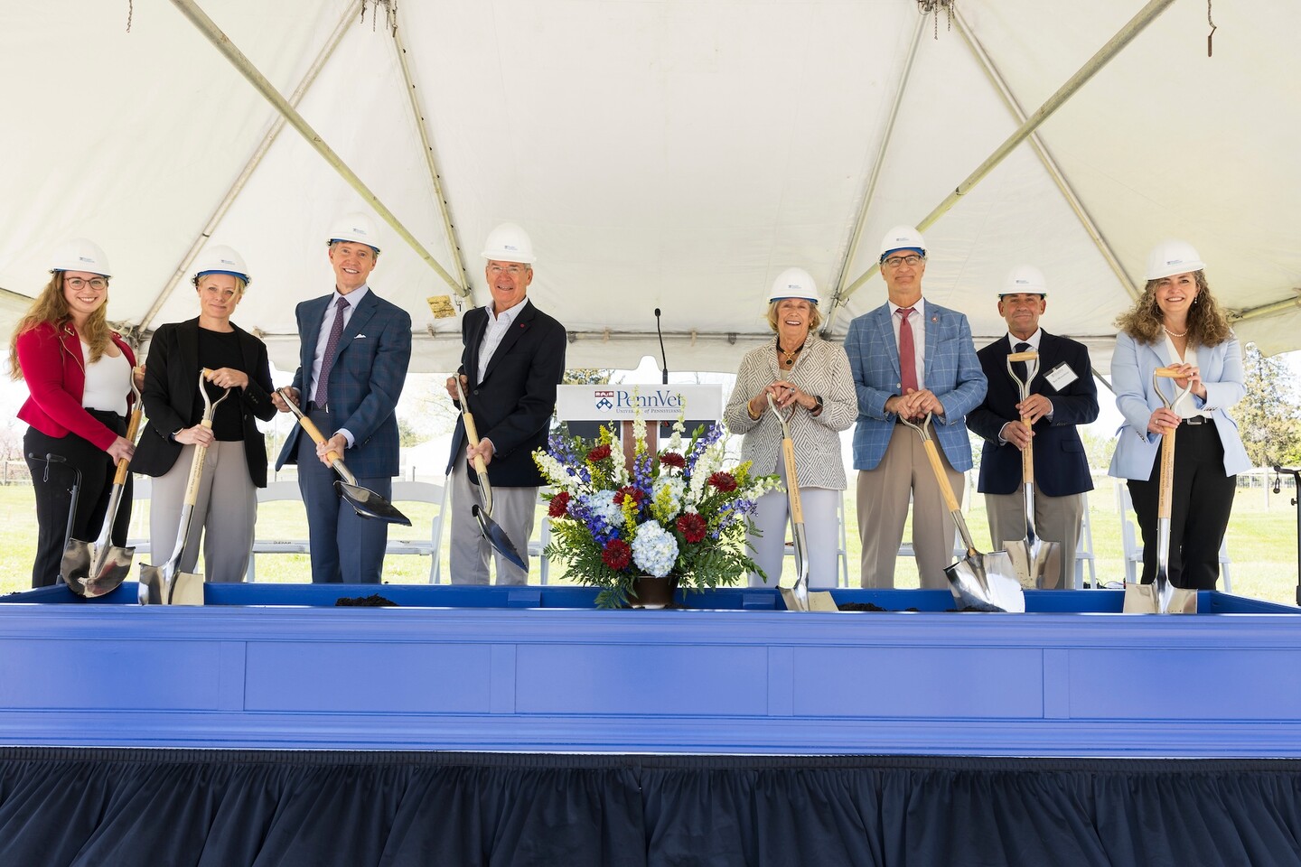 Eight people on stage with shovels for ceremonial groundbreaking.