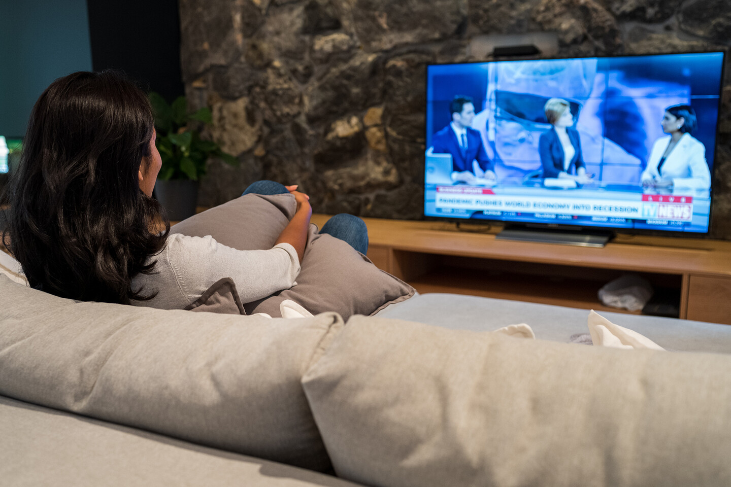 Person sitting on couch watching news.