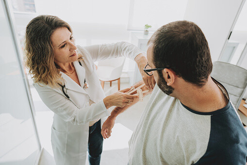 A doctor measuring the arm fat of a patient with calipers.